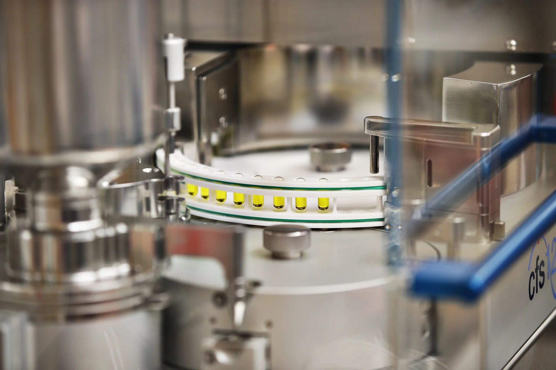 Automatisierte Verblisterungsanlage in der Apotheke, die Medikamente in Becher/Blister portioniert und über ein Förderband weiterleitet.