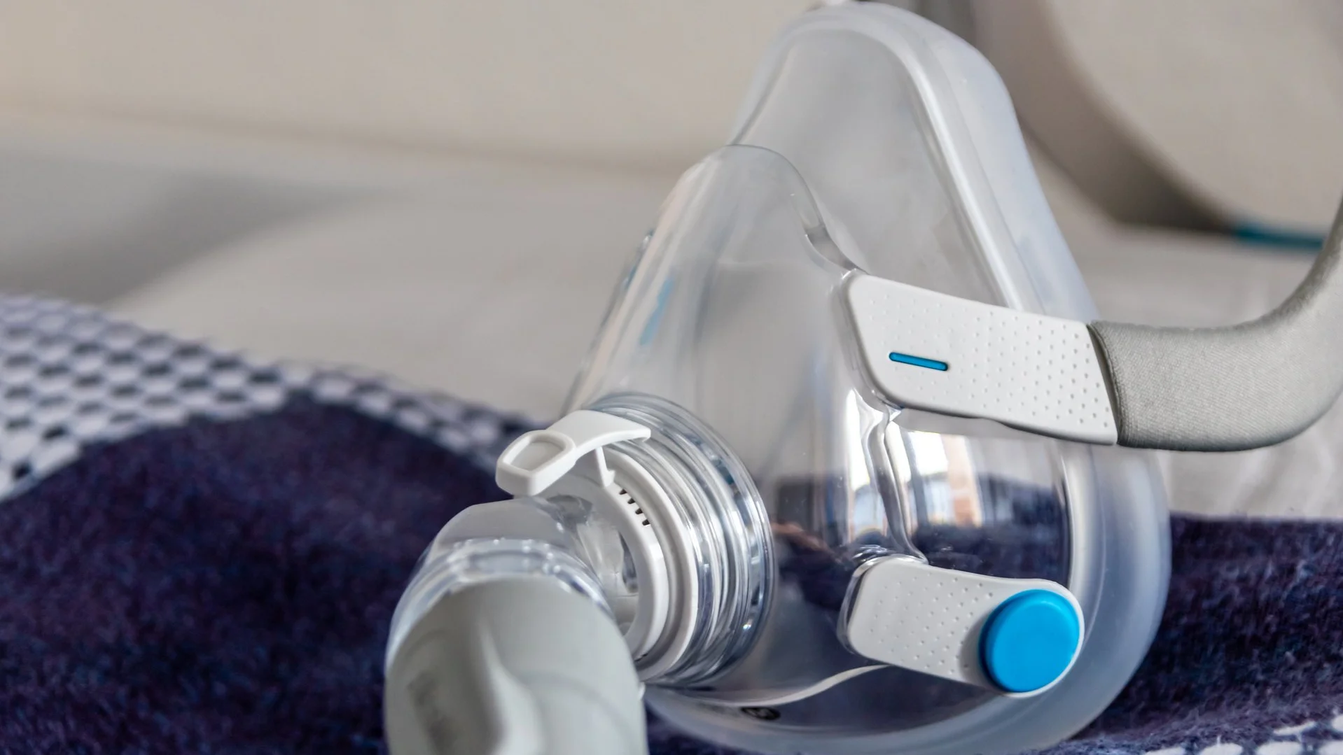 Atemmaske eines Inhalationsgeräts mit Schlauchanschluss liegt auf einer Decke.